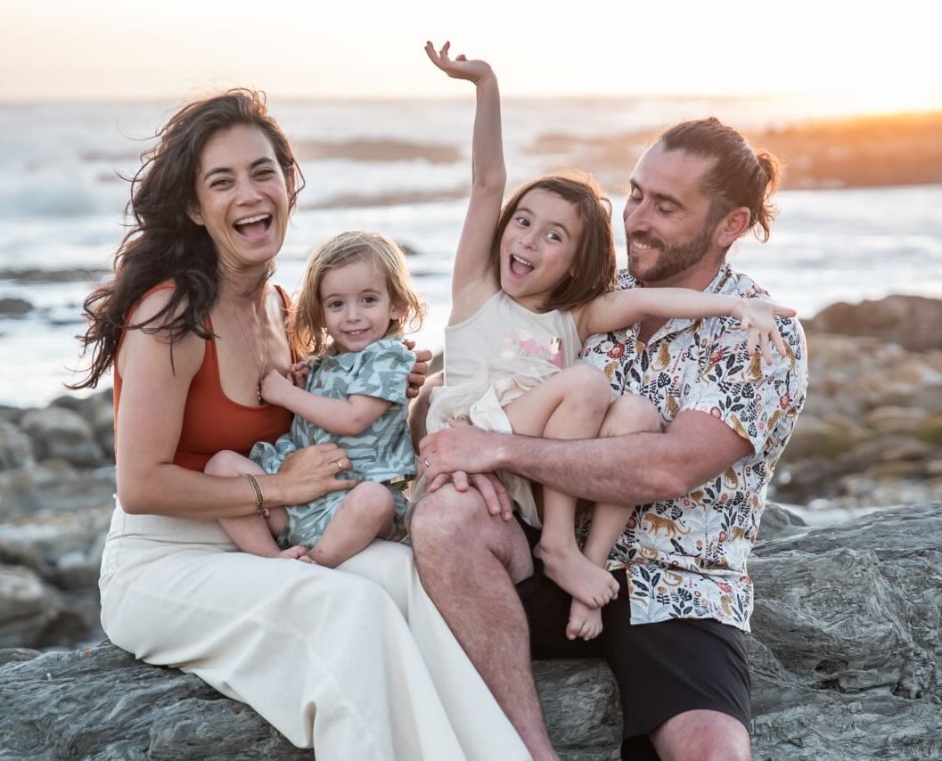Angelica, Lurian, Zuzu, and Josh on a rocky shoreline at sunset